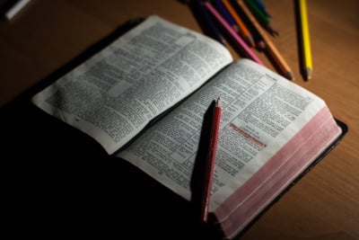 an open bible on a desk with colored pencils next to it for highlighting passages