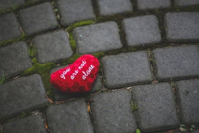 a red heart on brick pavers with the words you are not alone